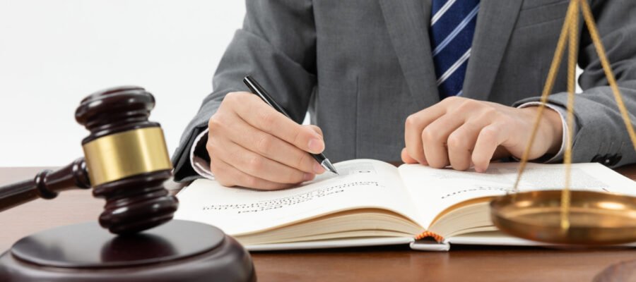 closeup-shot-person-writing-book-with-gavel-table